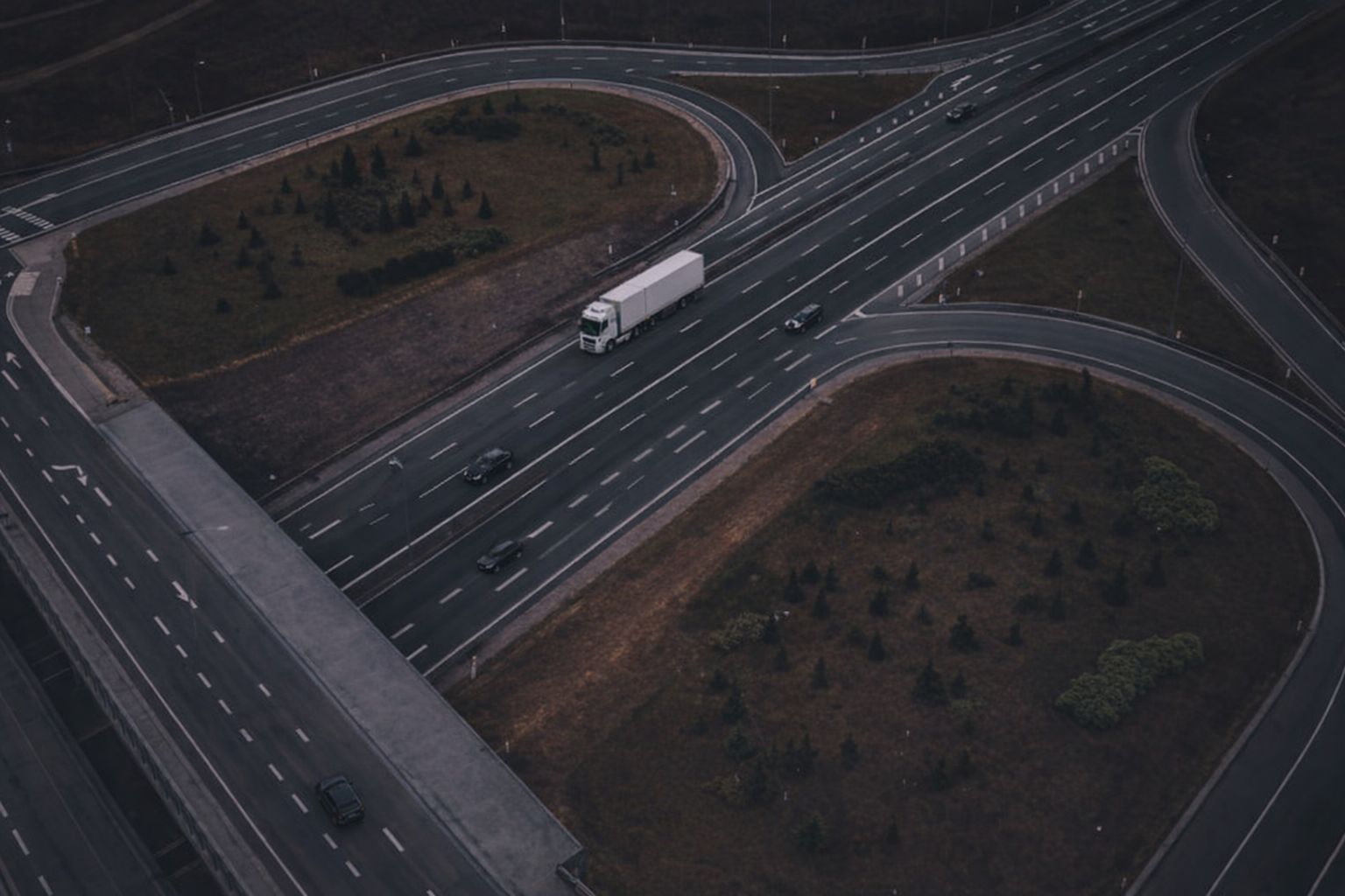 Luftaufnahme eines Autobahnkreuzes mit LKW und Autos in der Dämmerung.