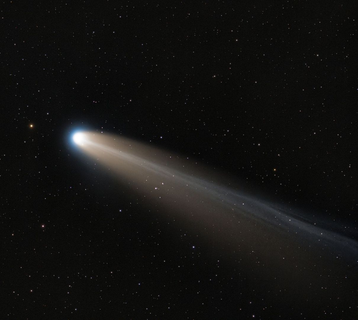 Heller Komet mit langem Schweif vor einem dichten Sternenhimmel